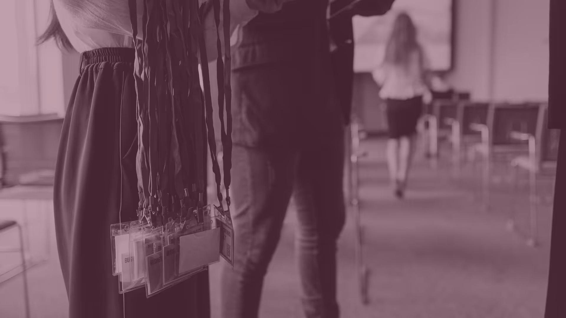 Person holding multiple event or conference lanyards with badge holders in a professional setting.