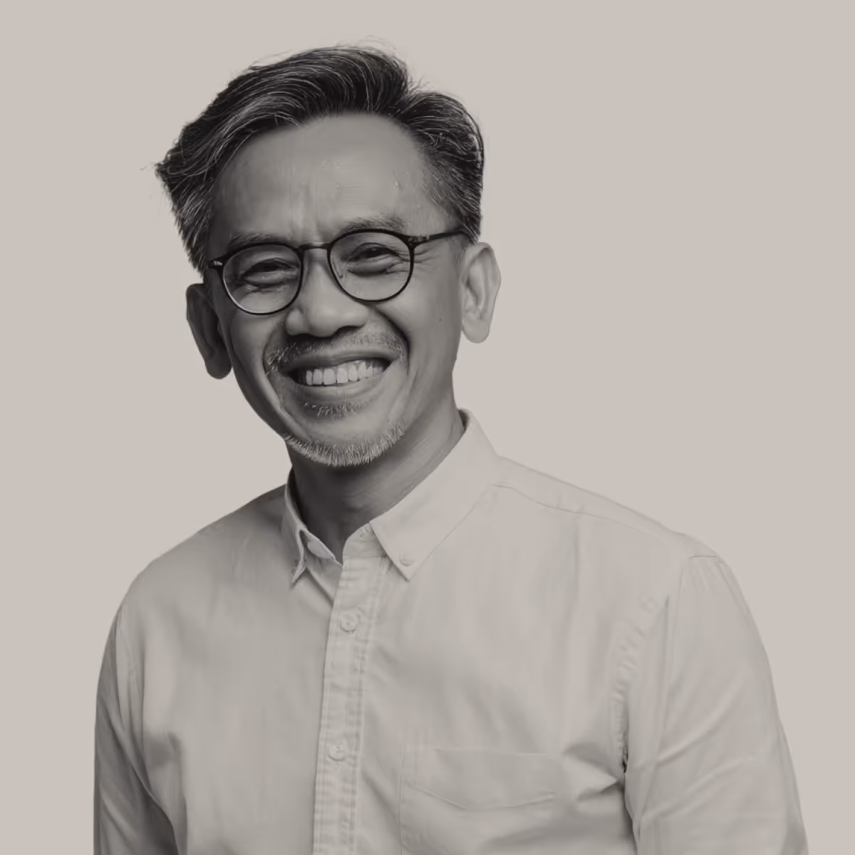 Smiling middle-aged man with glasses and gray hair wearing a buttoned-up shirt.