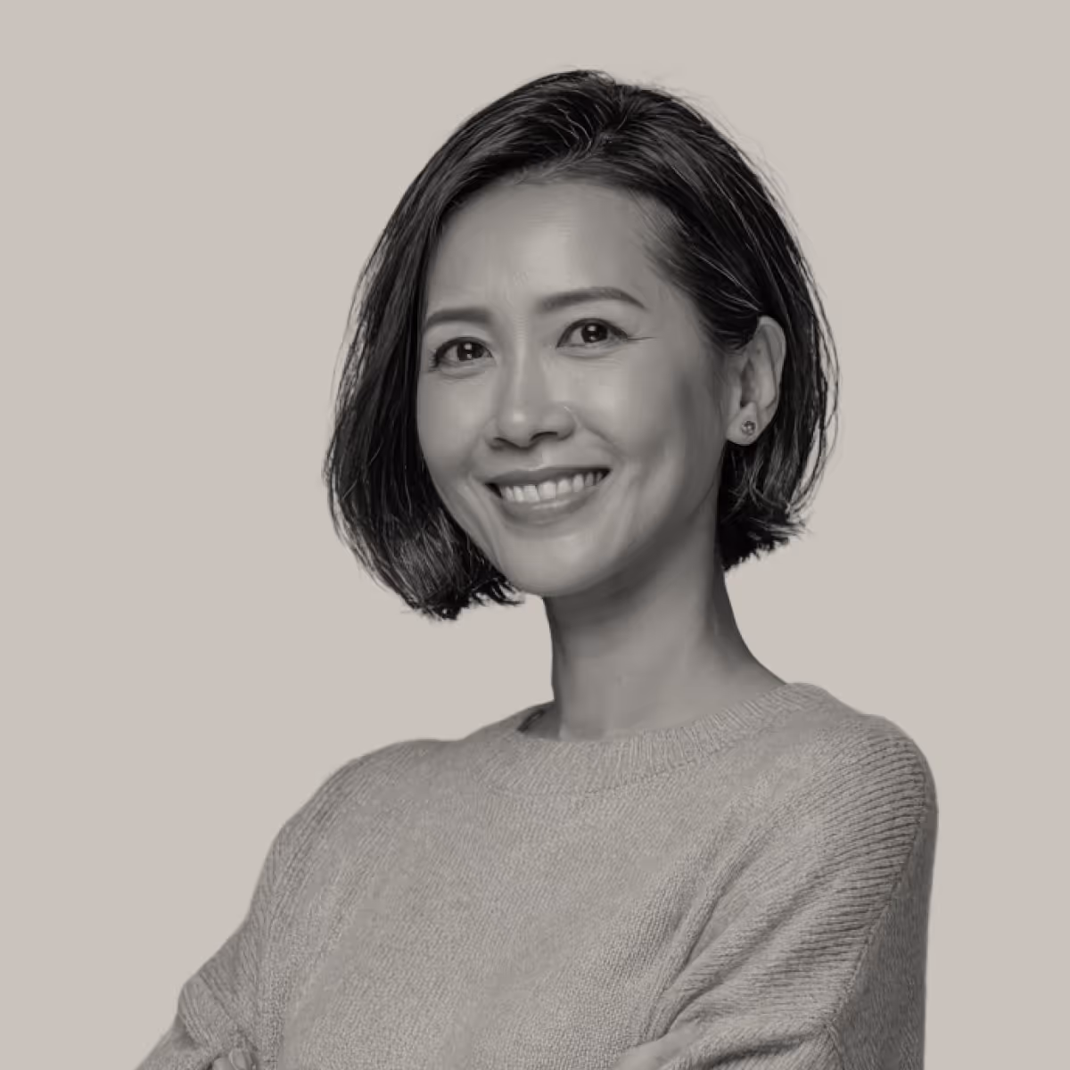 Smiling woman with short dark hair wearing a light sweater against a plain background.